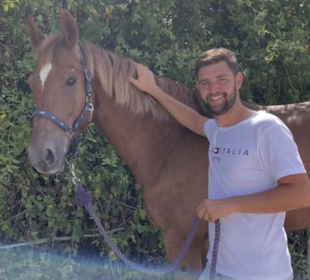 Diego junto a un caballo alazán al aire libre